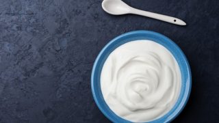 Top view of yogurt in a blue bowl and a spoon lying next to it