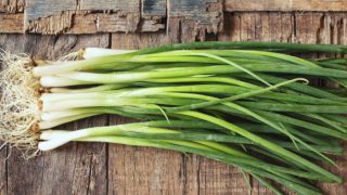 Green onion strands piled together on a wooden background