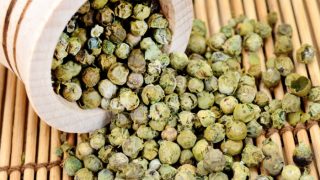 Green peppercorns spilling from a bottle