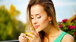 A woman breathing in the aromas of a tea in her hands