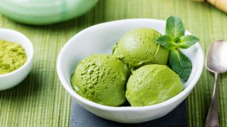 Matcha ice cream scoop in white bowl on a wooden background