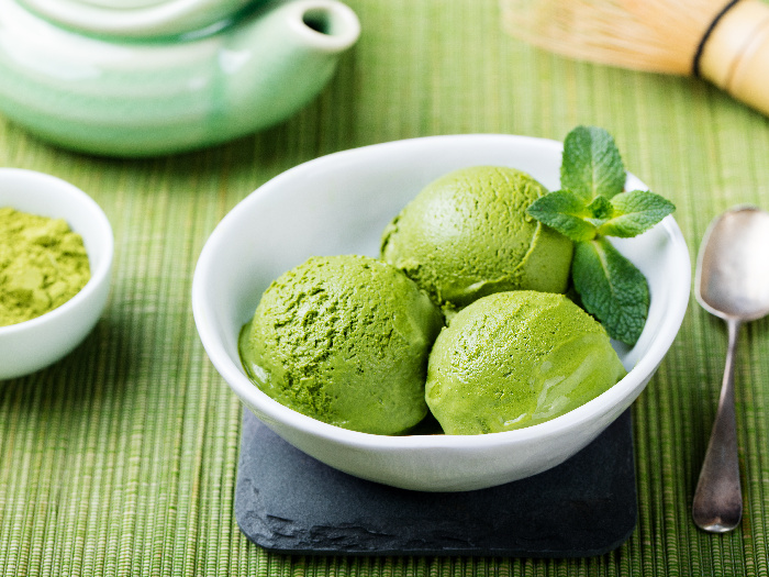 Matcha ice cream scoop in white bowl on a wooden background