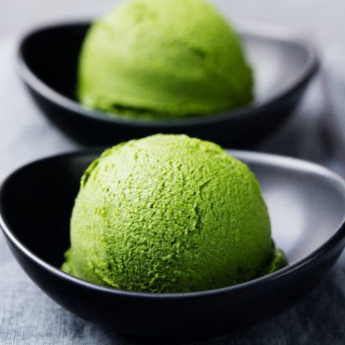 Matcha ice cream scoop in a bowl on a grey stone background