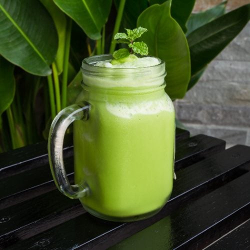 Green tea smoothie in glass on black wooden table