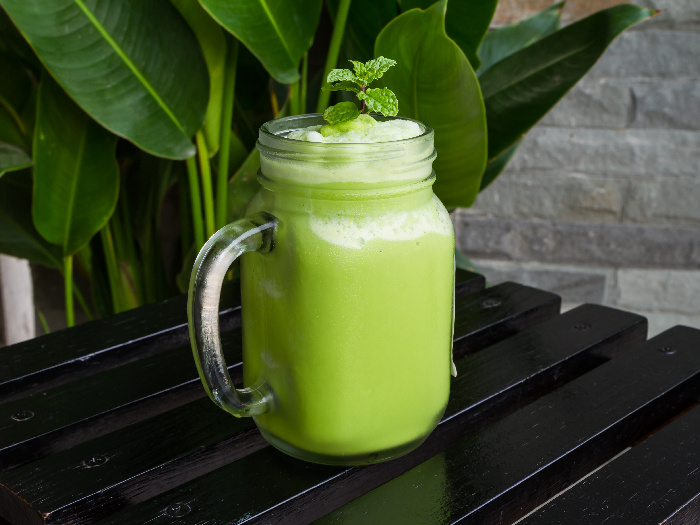 Green tea smoothie in glass on black wooden table