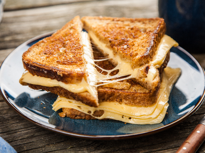 Grilled cheese sandwich on a blue plate on a wooden counter