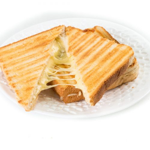 Grilled cheese sandwich on a white plate with cheese oozing out