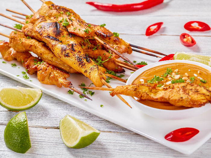 Grilled chicken skewers soaked in flavorful Asian marinade, with a bowl of satay sauce kept on the side as a dip