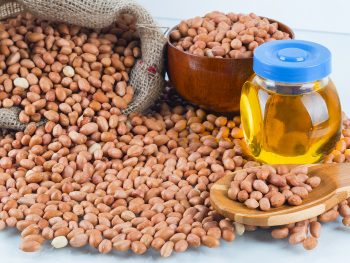 Groundnut oil with groundnuts on a sack, spoon and a bowl
