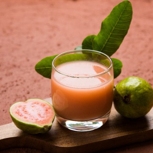 Red guava juice in a glass with a moody background