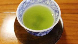 A white bowl of tea kept on a a wooden surface