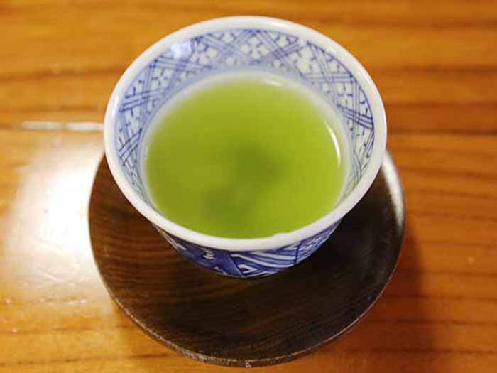 A white bowl of tea kept on a a wooden surface