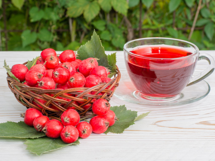 Basket of berries and a glass cup containing red tea on a white surface