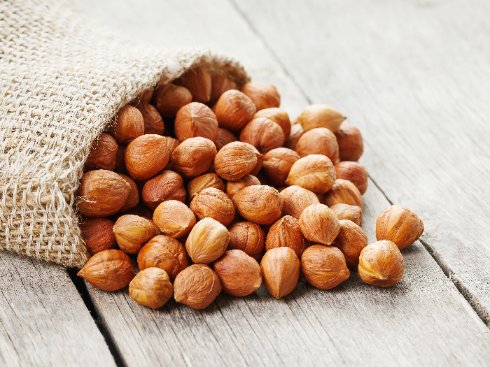 Chiselled hazelnuts in a bag of burlap on a gray wooden table