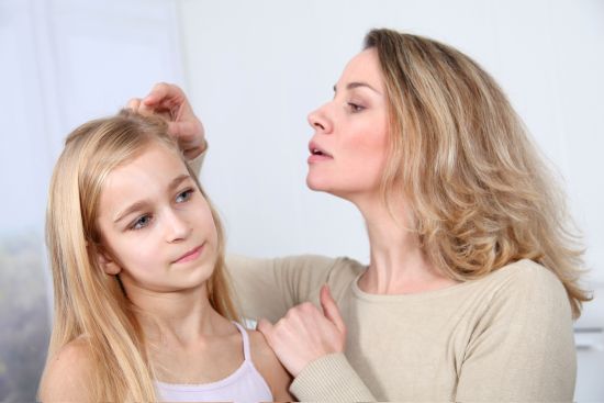 A mother removing head lice from her daughter's hair