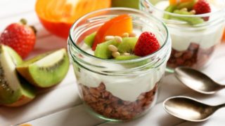 Healthy dessert made with granola, yogurt, seeds, sliced kiwi, persimmon, and strawberry
