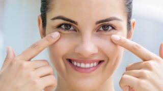 A woman smiling and pointing towards her healthy eyes
