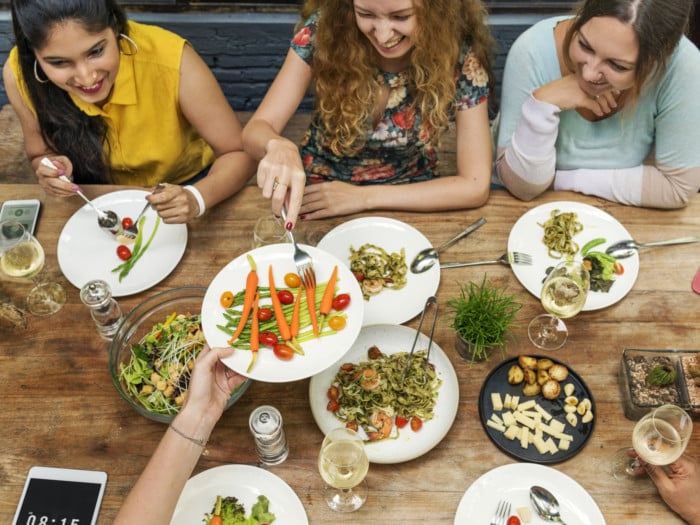 テーブルを囲んで食べ物を分け合う人たち