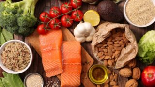 Fresh fruits, vegetables, nuts, cereals, salmon, and oil on wood