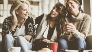 three women with coffee looking happy
