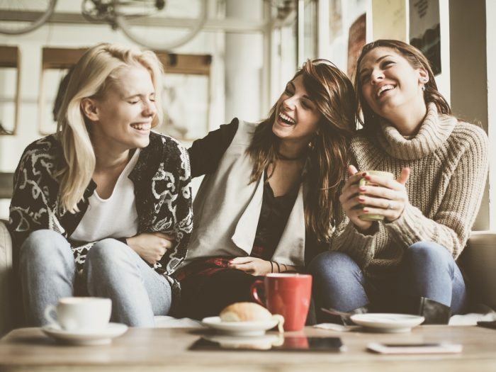 three women with coffee looking happy