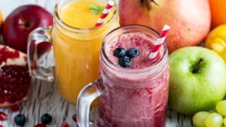 A mason jar filled with delicious fruit smoothies with assorted fruits spread aside