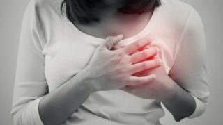 a woman in a white tshirt holding both her hands at her heart