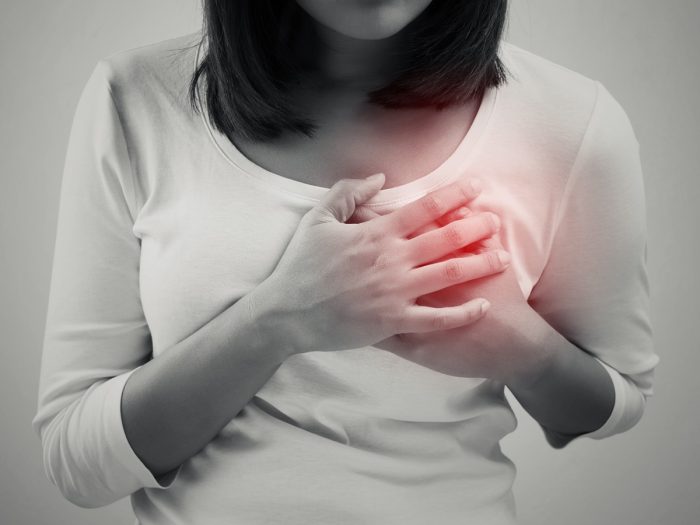 a woman in a white tshirt holding both her hands at her heart