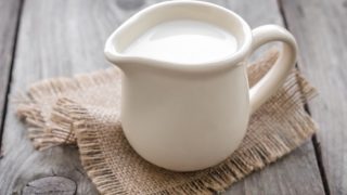 A mini white creamer filled with heavy cream kept on burlap