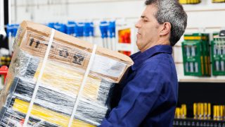 Mature male employee lifting a heavy load at work