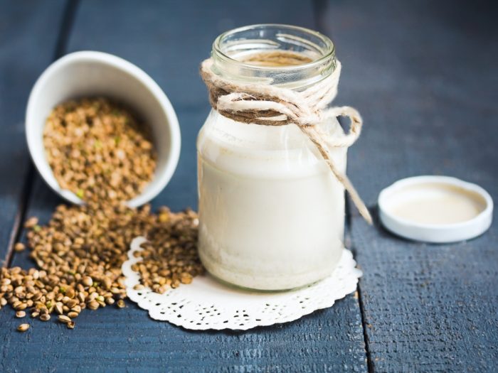 A glass jar filled with hemp milk kept next to a bowl of hemp seeds