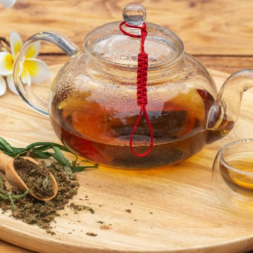 Cannabis herbal tea, marijuana leaf, cup and teapot on wood table