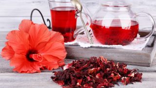 Dried hibiscus leaves and hibiscus tea on a wooden table