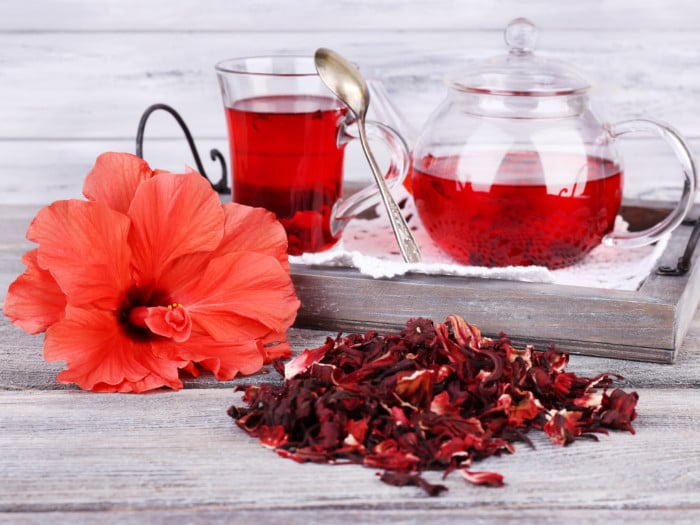 Dried hibiscus leaves and hibiscus tea on a wooden table