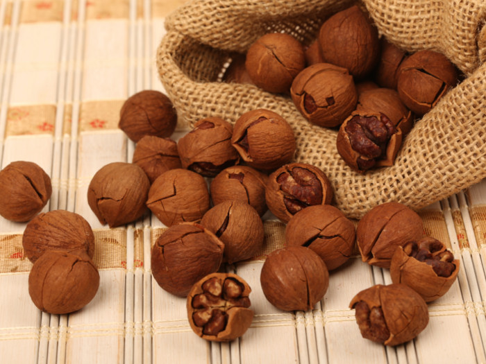 Hickory nuts falling from a jute bag on a placemat