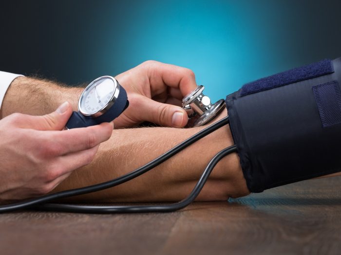 A doctor using a blood pressure monitor or sphygmomanometer on a patient to check high blood pressure levels