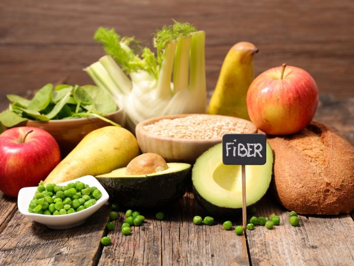 Vegetables and fruits placed on a rough wooden surface with a small board saying 'FiBER' on a board at the front.