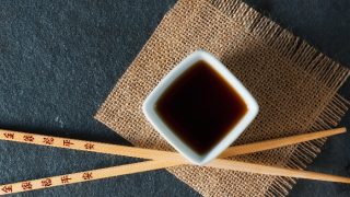 A flat lay shot of chopsticks resting across a small bowl of hoisin sauce.