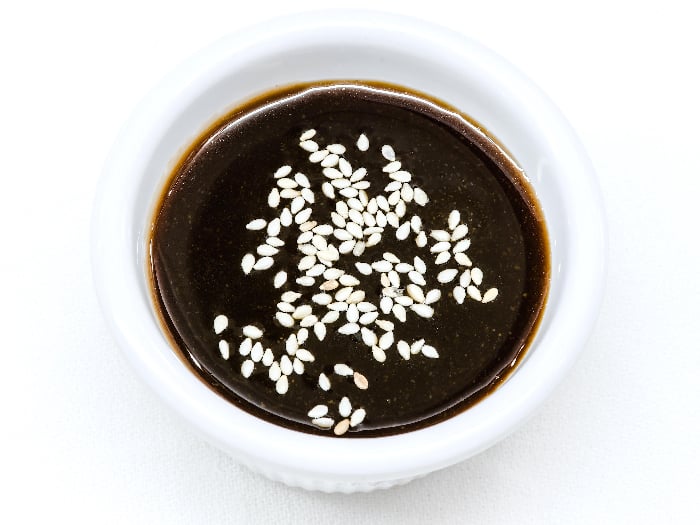 Hoisin sauce topping with sesame seeds, kept in a white bowl against a white background