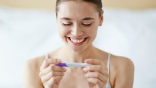 A smiling woman checking a home pregnancy test