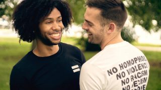 Two men standing in a park, looking at each other