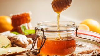 A jar of honey with ginger and lemon on a wooden table