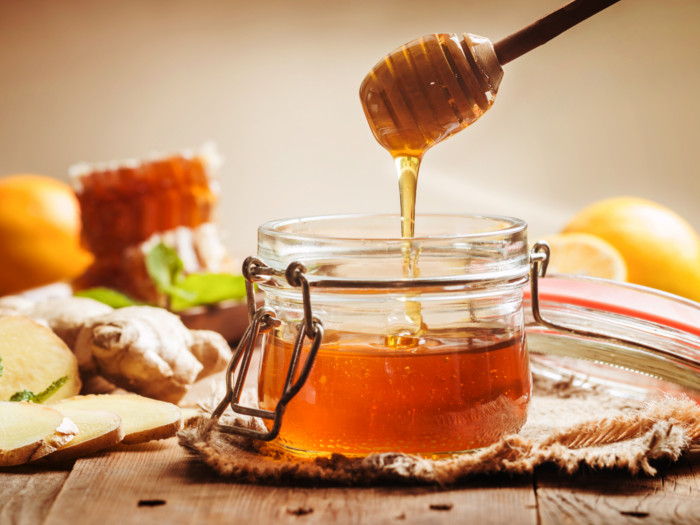 A jar of honey with ginger and lemon on a wooden table