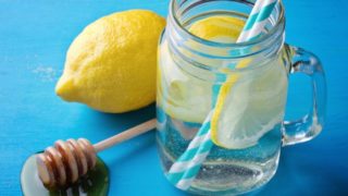 Lemon water and straws in a jar and two lemons near it