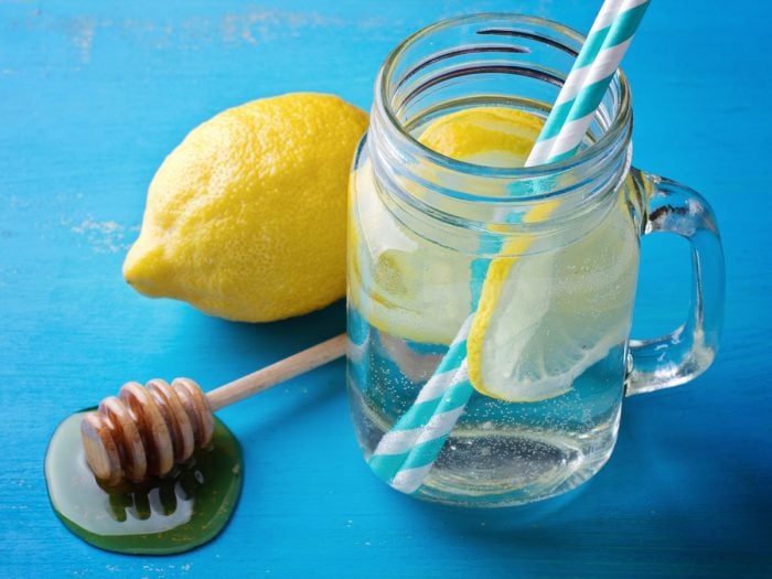 Lemon water and straws in a jar and two lemons near it