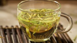 A cup of honeysuckle tea on a wooden mat