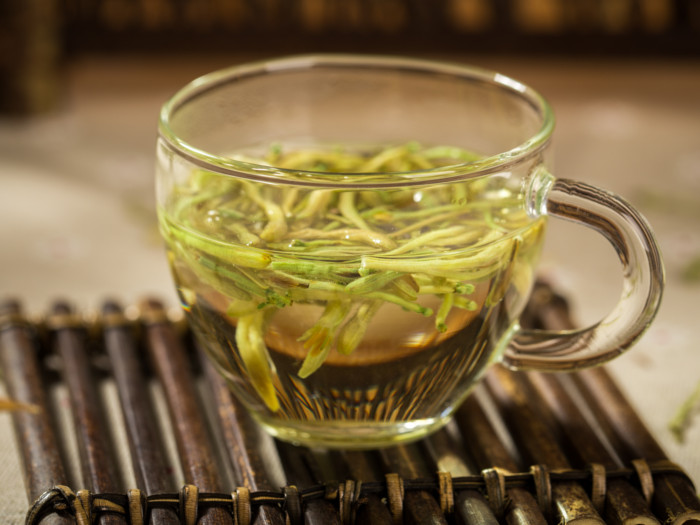 A cup of honeysuckle tea on a wooden mat