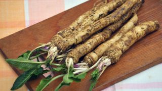 Fresh horseradish with leaves on a wooden chopper board