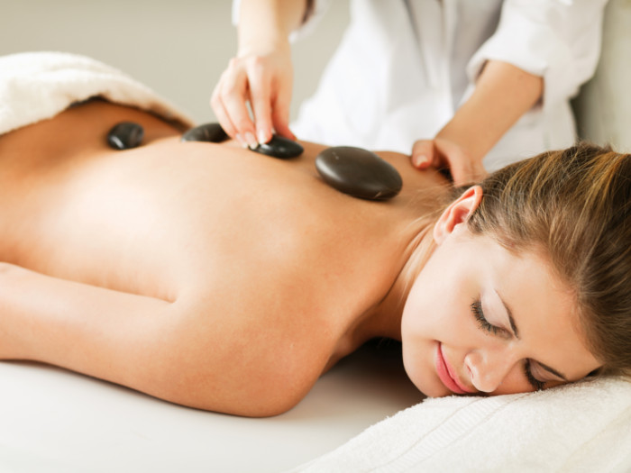 A woman on a spa bed, getting a hot stone massage