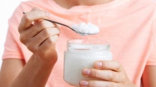 Close up of a young woman with a bottle and spoonful of coconut oil
